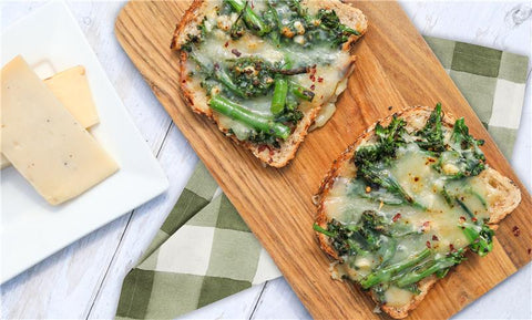 Open faced cheese melt with broccolini on a board