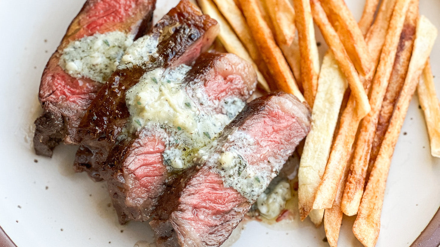 steak frietes with bay blue compound butt on a plate