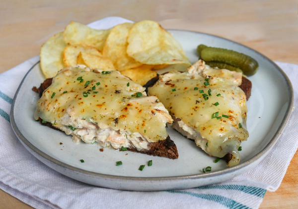 open faced tuna melt on a plate with chips and pickles