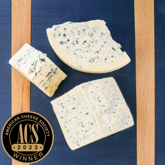 original blue cheese on blue cheeseboard with american cheese society logo overlayed on the photo