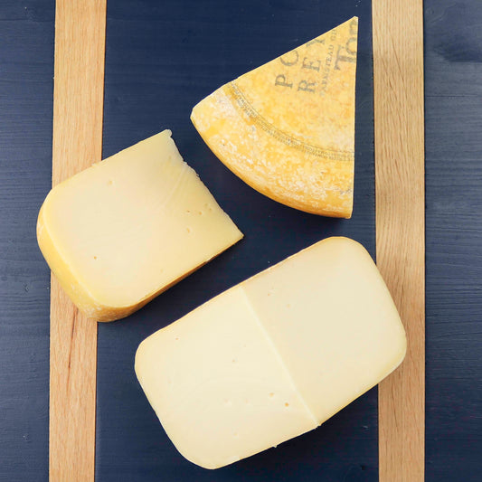 Toma cheese cut into pieces on a blue cheeseboard