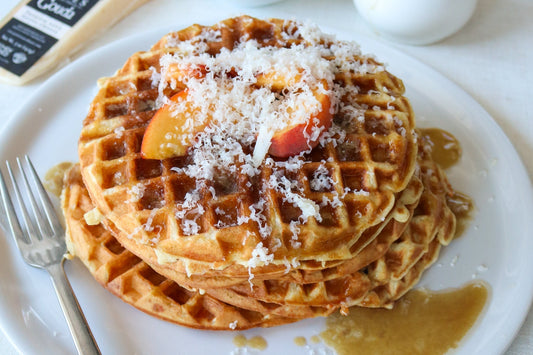 waffles with shaved Gouda, peaches and syrup on a plate