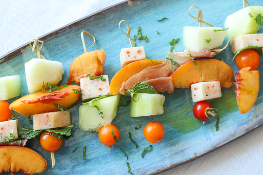 melon, stone fruit & tomarashi skewers on a blue platter