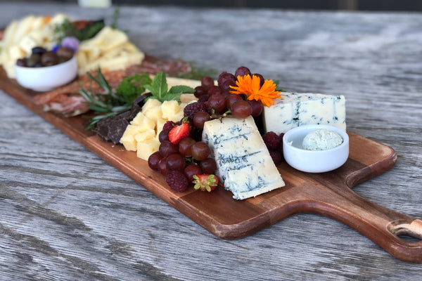 a cheeseboard with edible flowers and fresh herbs