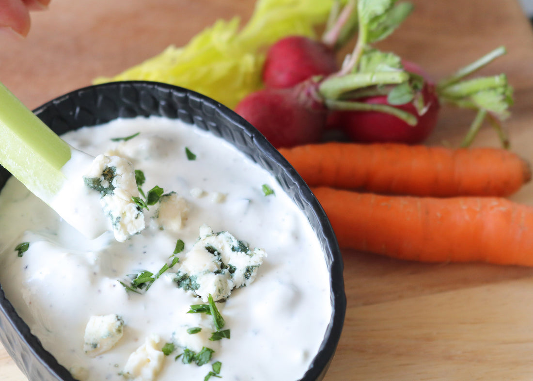 Celery stick dipping into Creamy Original Blue Dressing