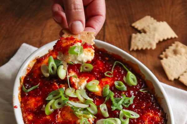 baked cheese in a casserole dish with chili jam and crackers 