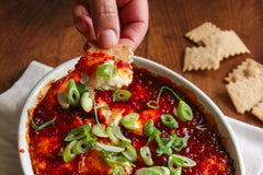baked cheese in a casserole dish with chili jam and crackers 