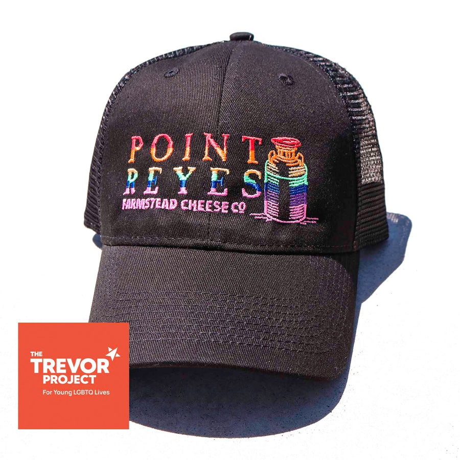 a black baseball hat with a rainbow point reyes farmstead logo and the trevor project logo