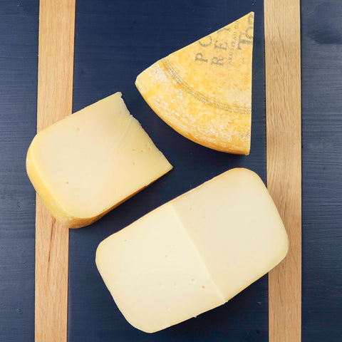 Product: Toma cheese cut into pieces on a blue cheeseboard