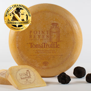 A wheel and two wedges of TomaTruffle with the World Champion Cheese Competition logo