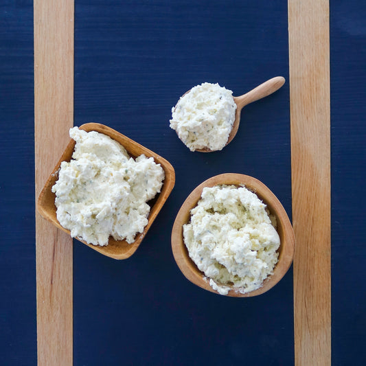 Three bowls of TomaTruffle cheese spread on a blue cheeseboard
